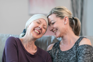 A woman with cancer laughs with her friend who is offering support.