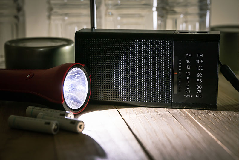 A battery-operated radio and flashlight symbolize power outage tips for seniors.