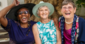 Three older women who understand optimistic aging smile broadly.