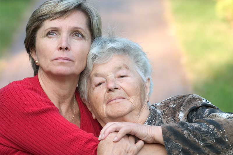 A woman hugs her aging mother, wondering if she is at risk for inheriting Alzheimer’s.