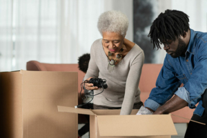 A man who knows how important it is to involve your parents in decluttering their home works with his aging mother to pack up boxes.