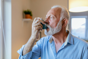 A man who is managing COPD comorbidities uses an inhaler.