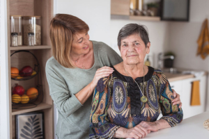 A woman places her hand on her mother’s shoulder, comforting her as she experiences dementia time-shifting.