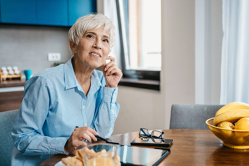 A woman struggling with making decisions as a dementia caregiver stares off into the distance with a confused expression on her face.