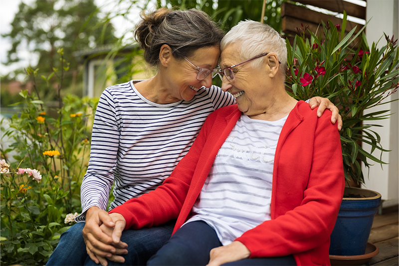 A caregiver demonstrates one of many nonverbal ways to communicate with someone with Alzheimer’s by holding hands and sharing a warm smile.