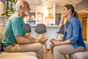 A man experiencing speech difficulties in Parkinson’s sits across from his caregiver as they work on exercises to help.